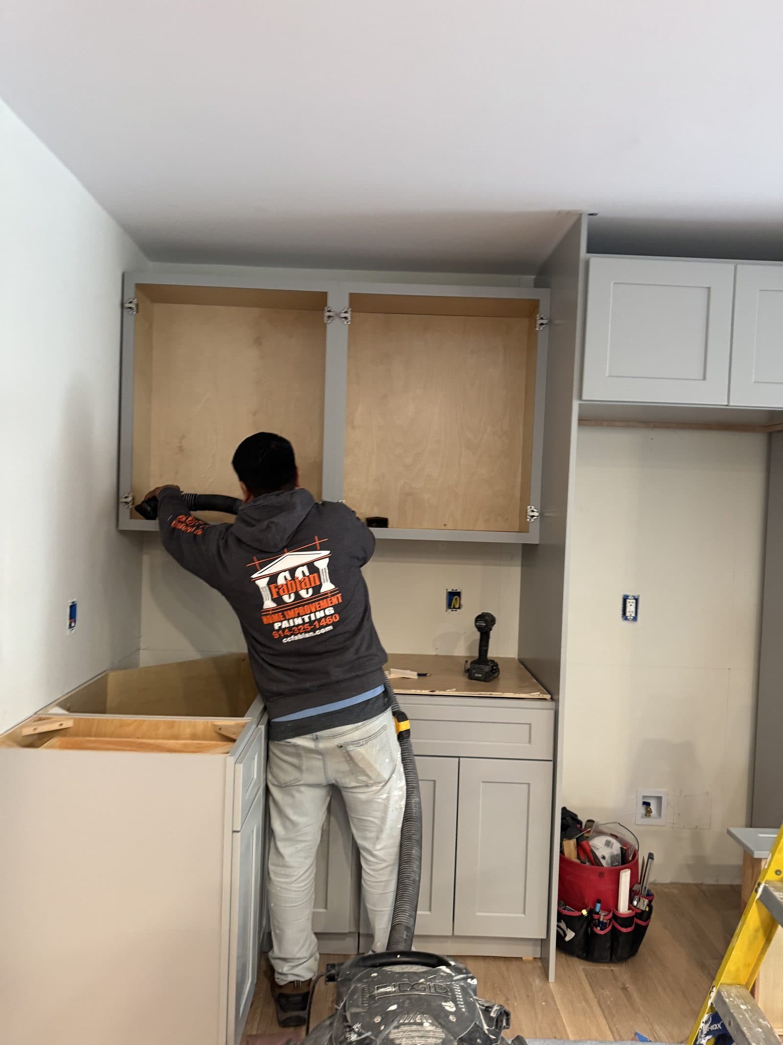 C&C Fabian carpenter installing custom kitchen cabinetry.