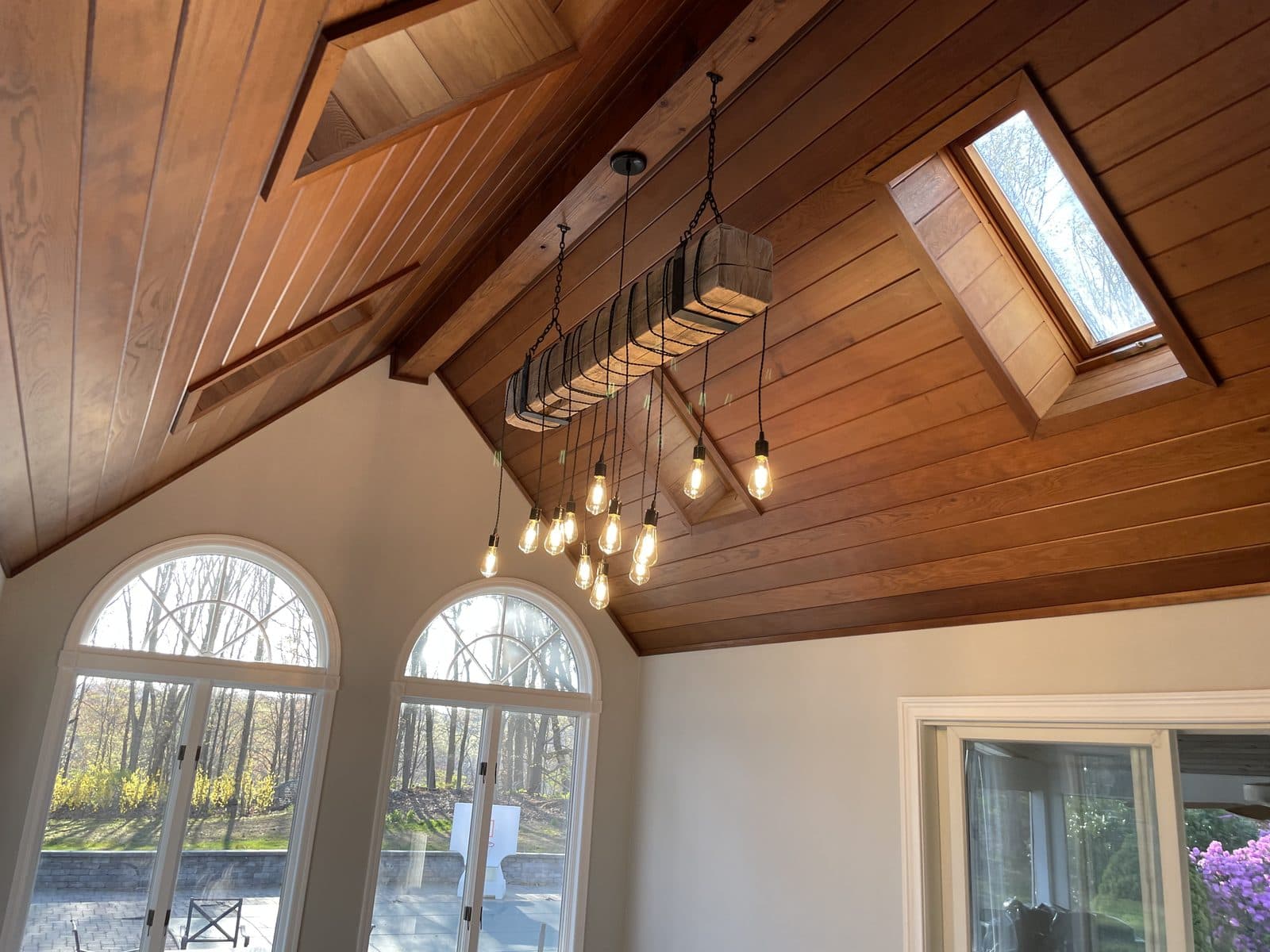 Interior with vaulted wood ceiling, chandelier, and arched windows.