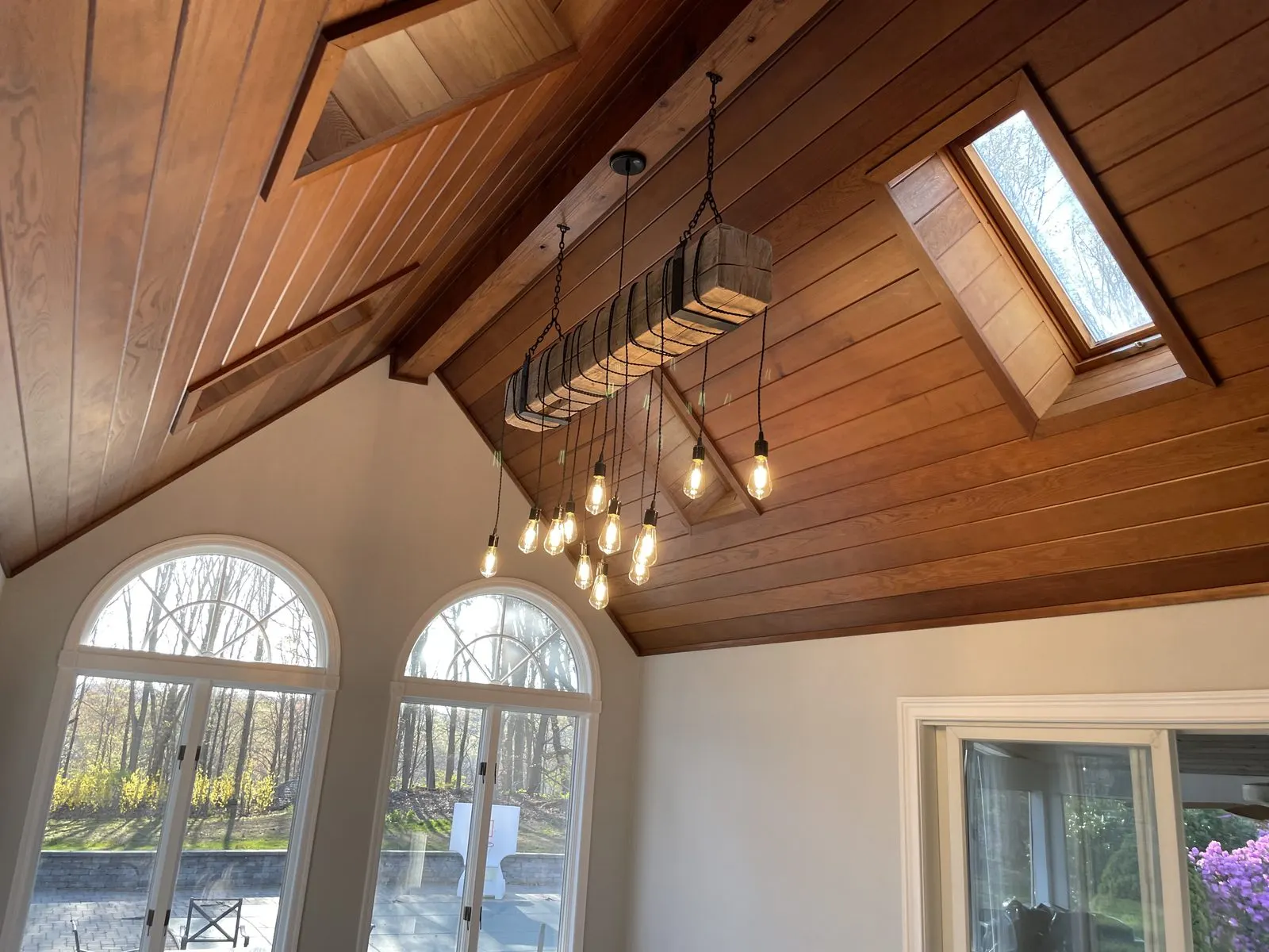 Interior with vaulted wood ceiling, chandelier, and arched windows.