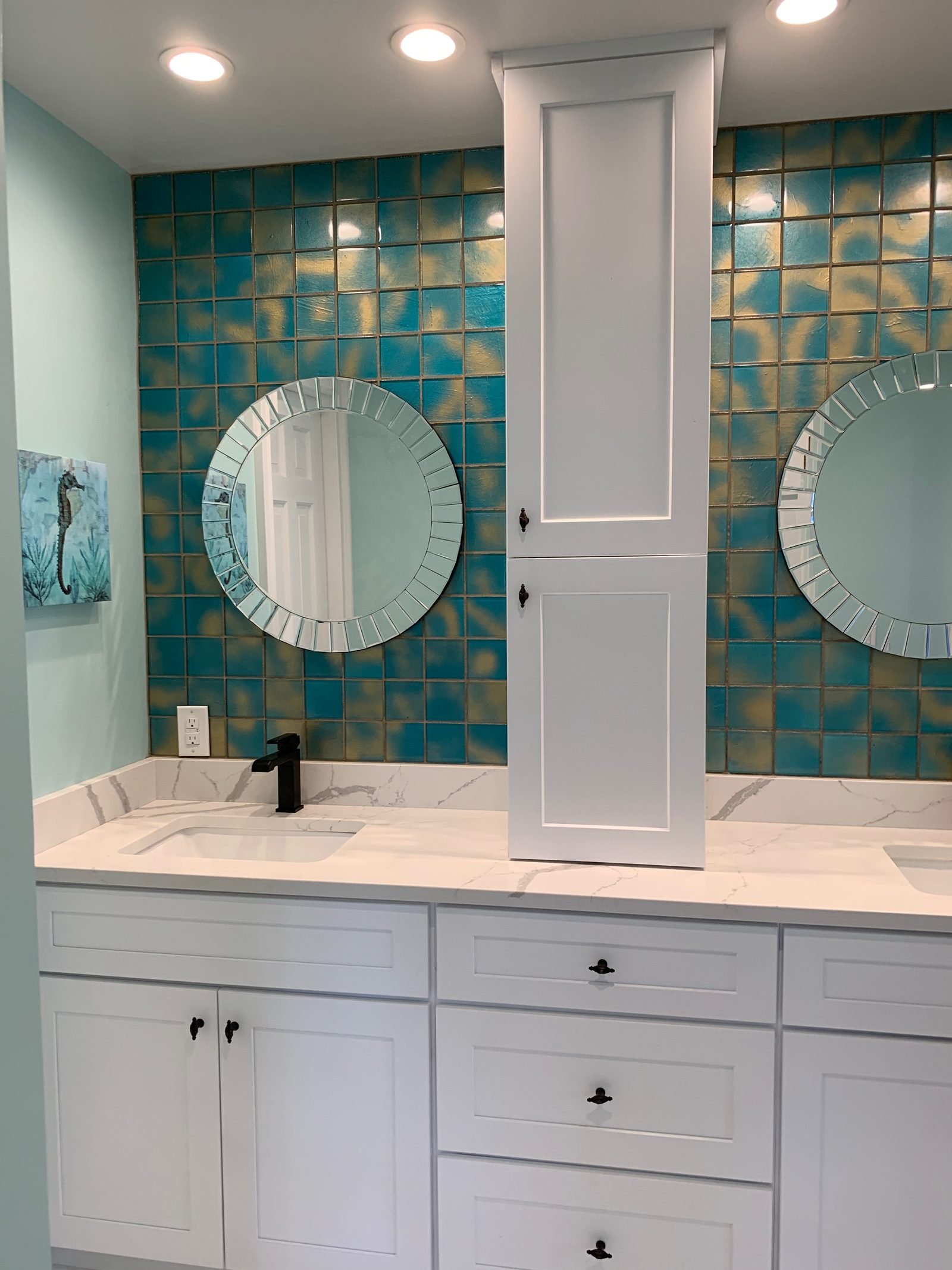 Finished bathroom remodel with a white double vanity, round mirrors and teal glass tile
