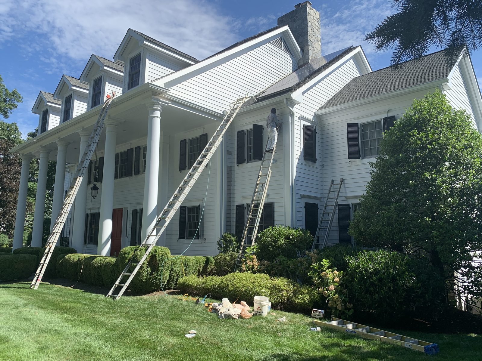 White colonial house with ladders