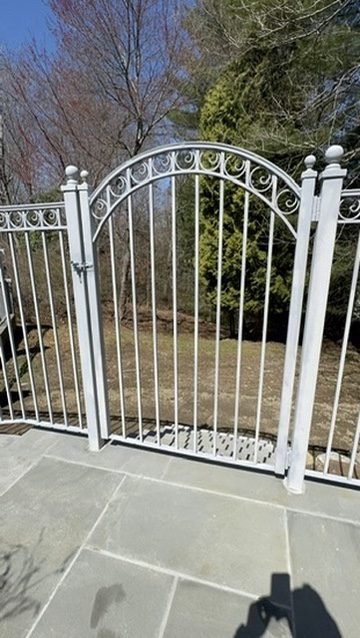 White ornamental arched garden gate on a stone patio