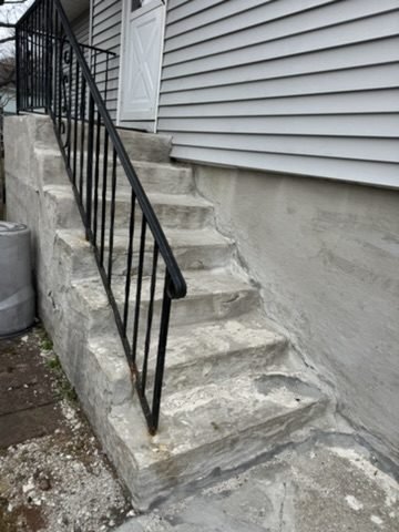 Black iron handrail installed along stone steps