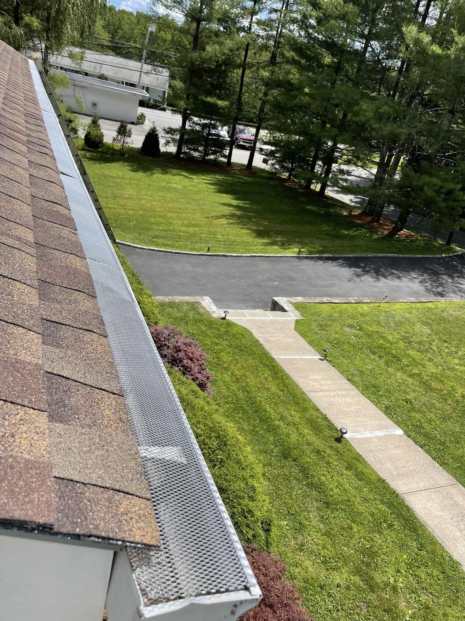 Freshly installed gutter guard running along a roofline above a manicured lawn