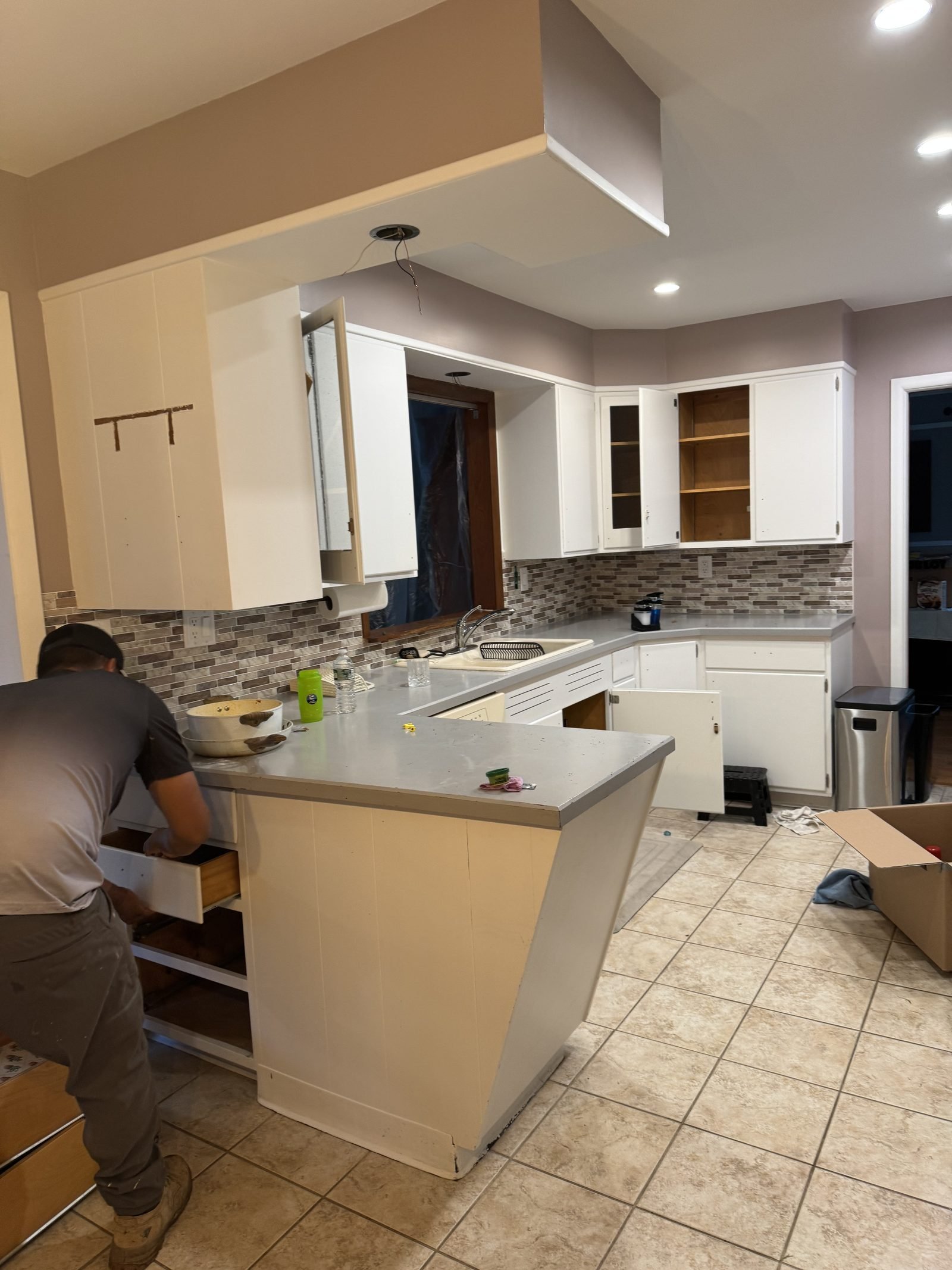 Original kitchen with white cabinets and dark backsplash before remodel