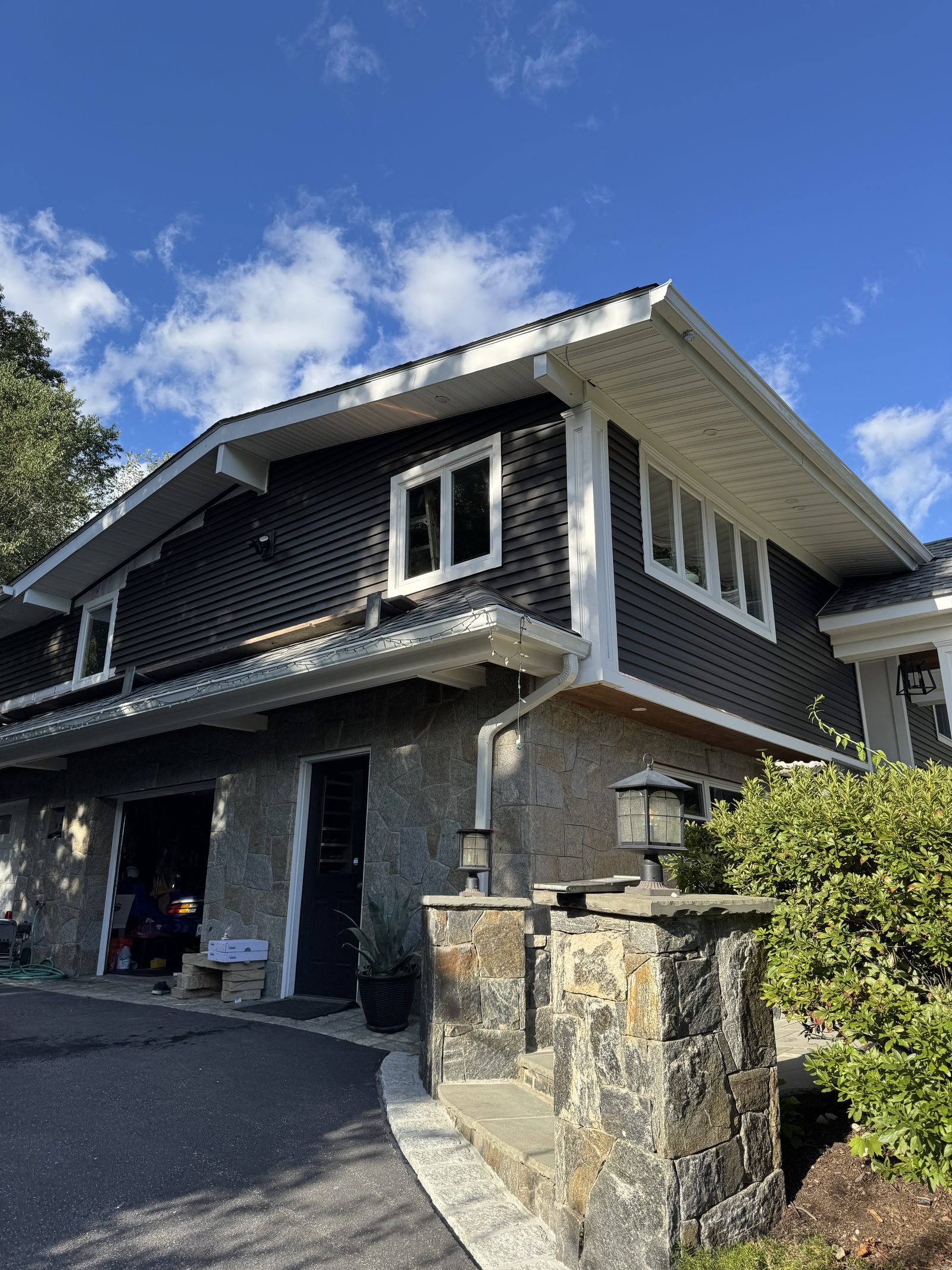 Dark gray sided home with stone pillars and white trim
